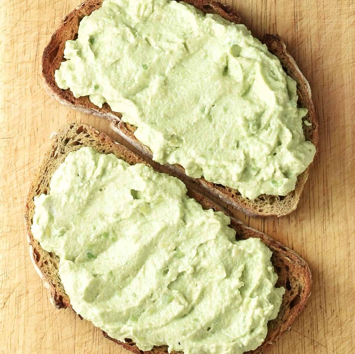 Top down view of creamy avocado and ricotta on 2 slices of toast.