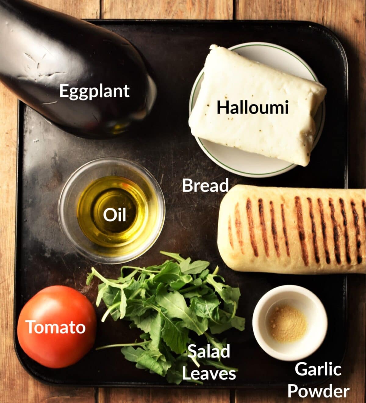 Eggplant sandwich ingredients on top of black tray.