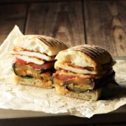 Side view of eggplant sandwich cut in half on top of paper.