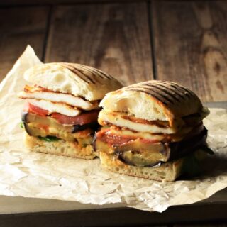 Side view of eggplant sandwich cut in half on top of paper.