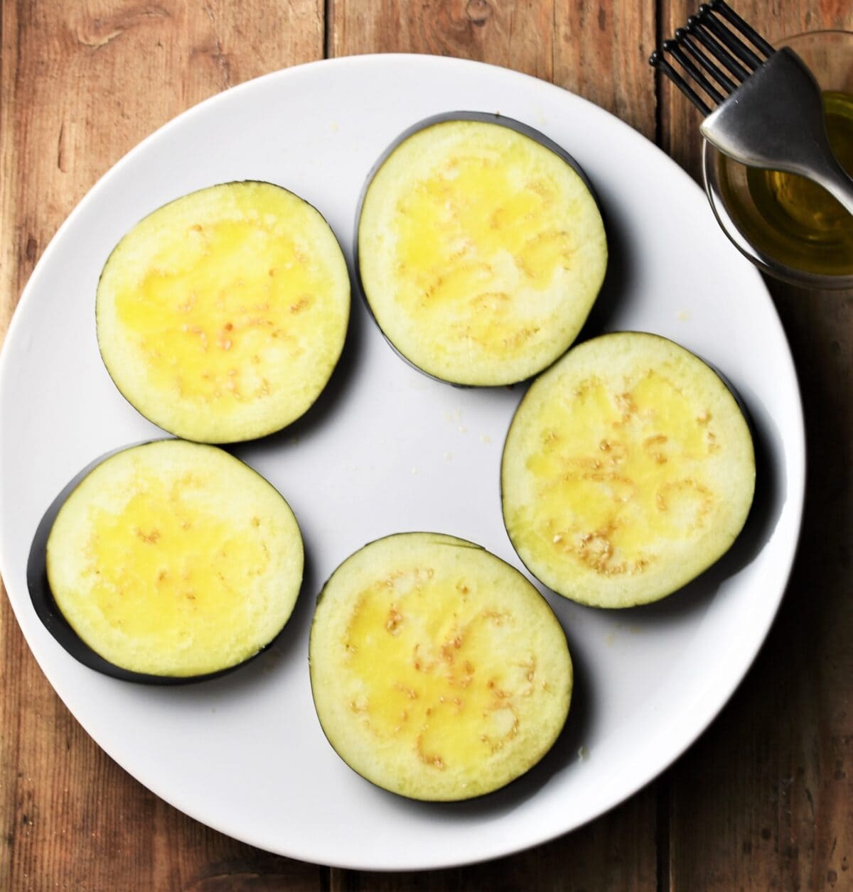 5 eggplant slices on top of white plate.