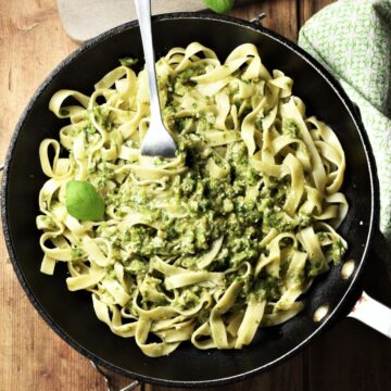 Top down view of asparagus pesto pasta in pan with fork.