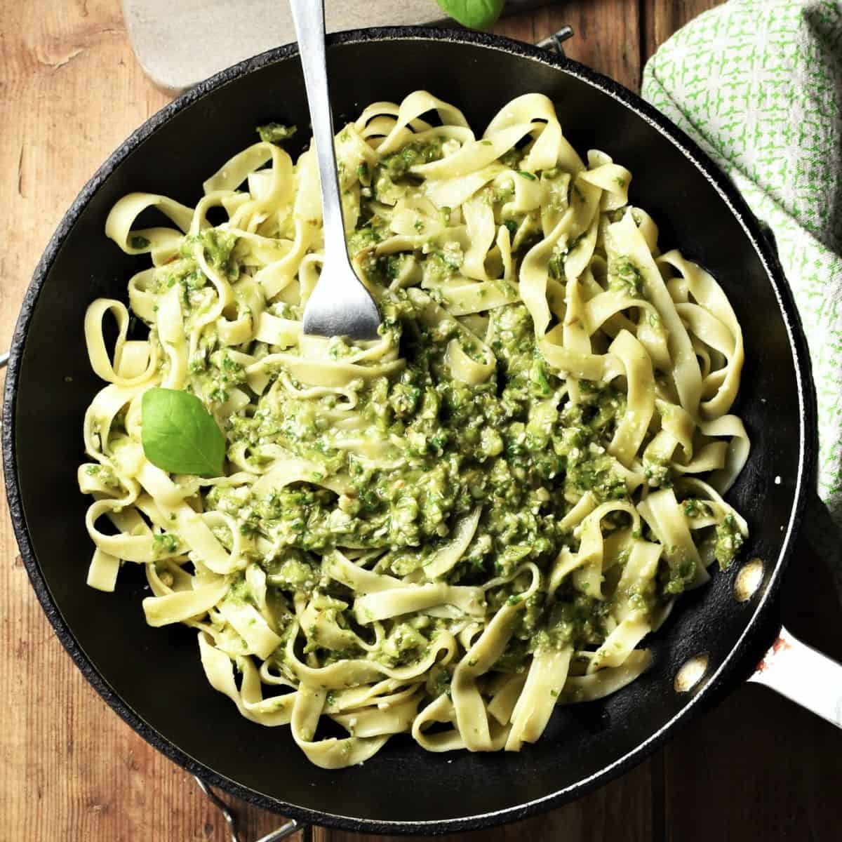 Top down view of asparagus pesto pasta in pan with fork.