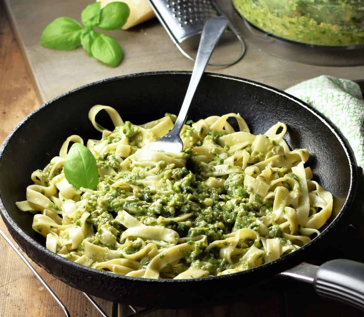 Side view of pasta with asparagus pesto in pan with fork.