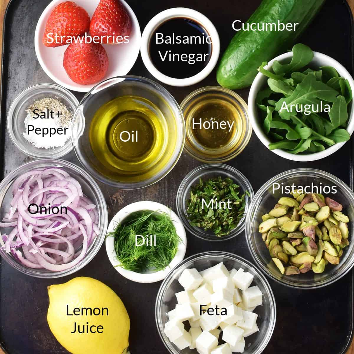 Top down view of strawberry cucumber salad ingredients in individual dishes.