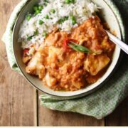 Top down view of fish lentil stew with rice in green bowl with spoon.