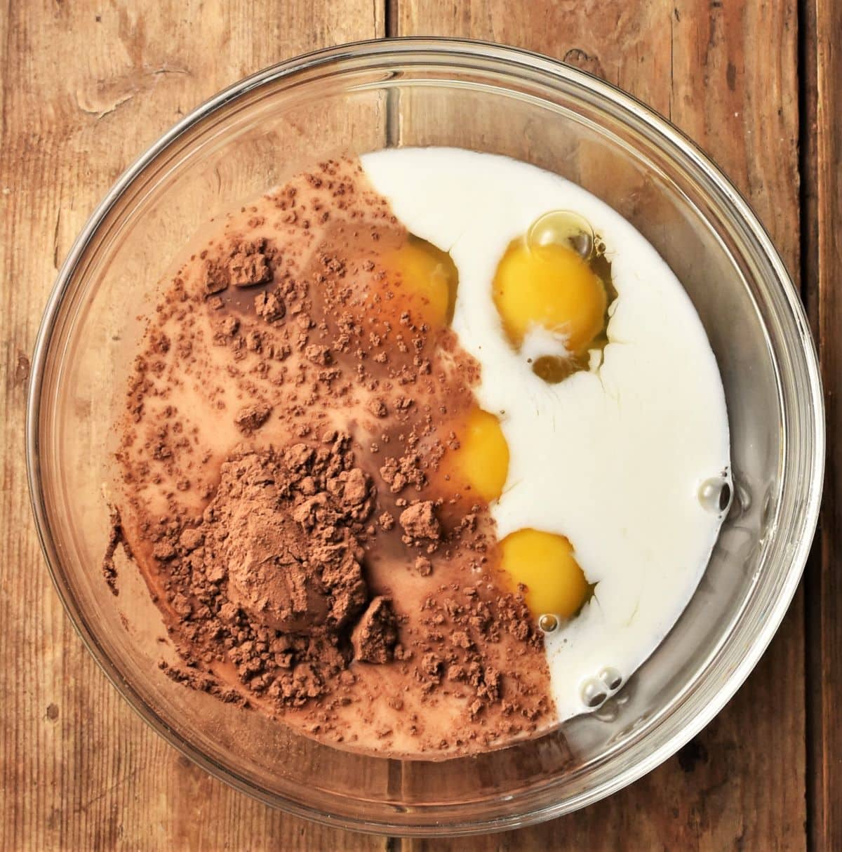 4 eggs, milk and cocoa in mixing bowl.