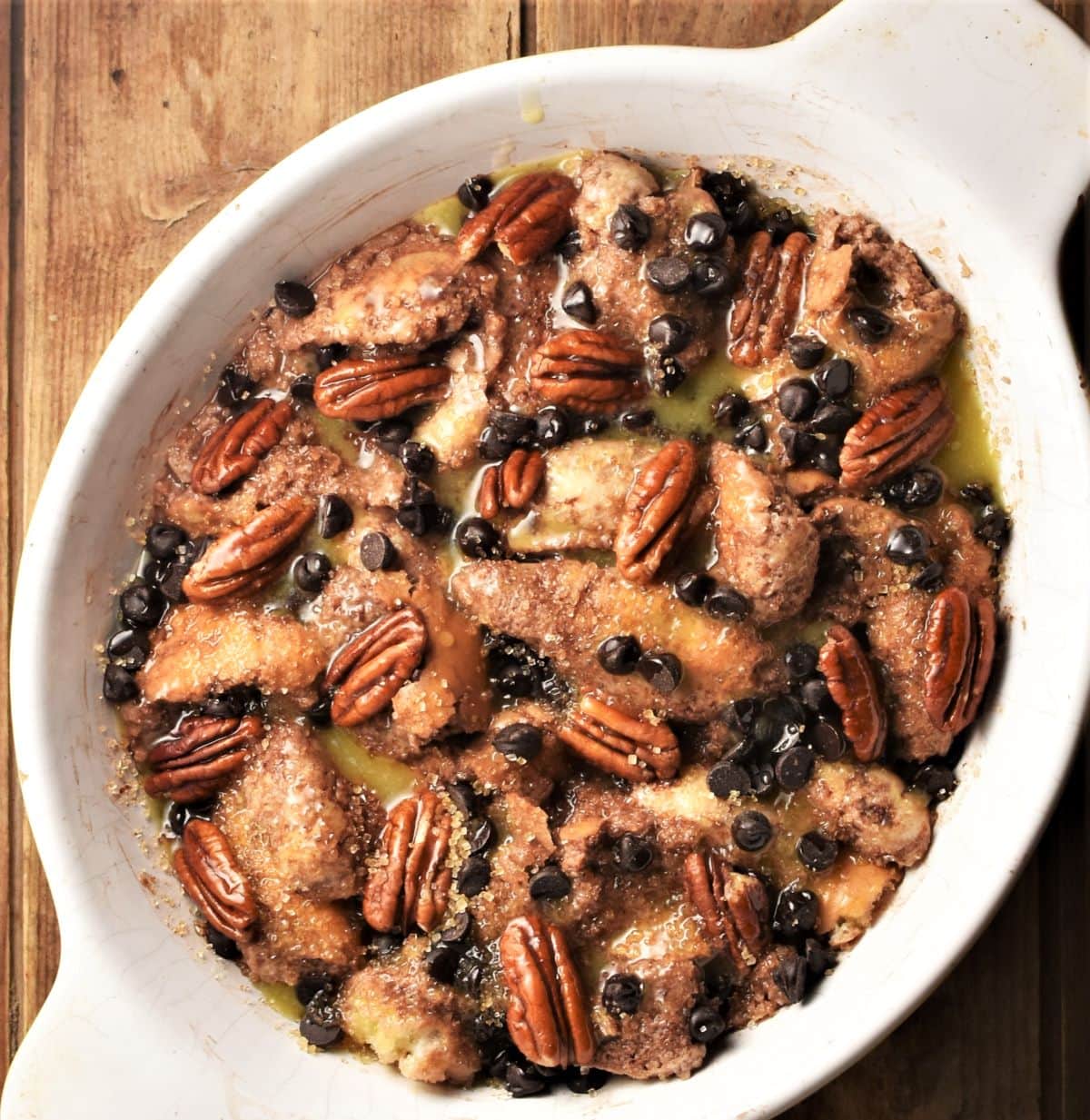 Chocolate french toast mixture with pecans and chocolate chips in white casserole dish.