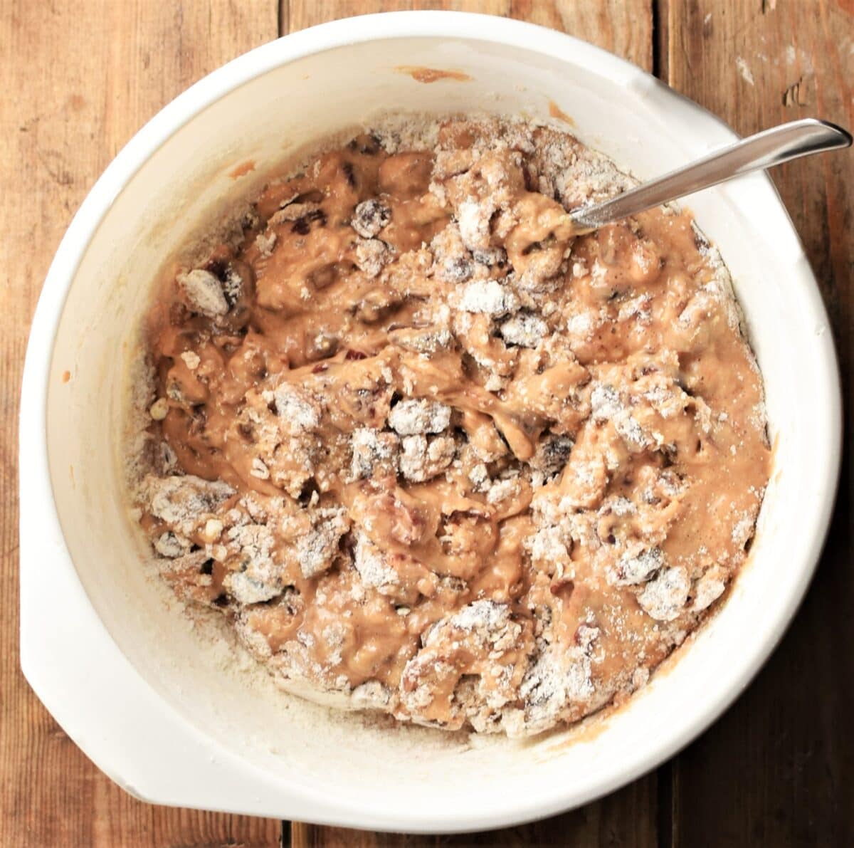 Tea bread batter with some flour visible in white bowl with spoon.