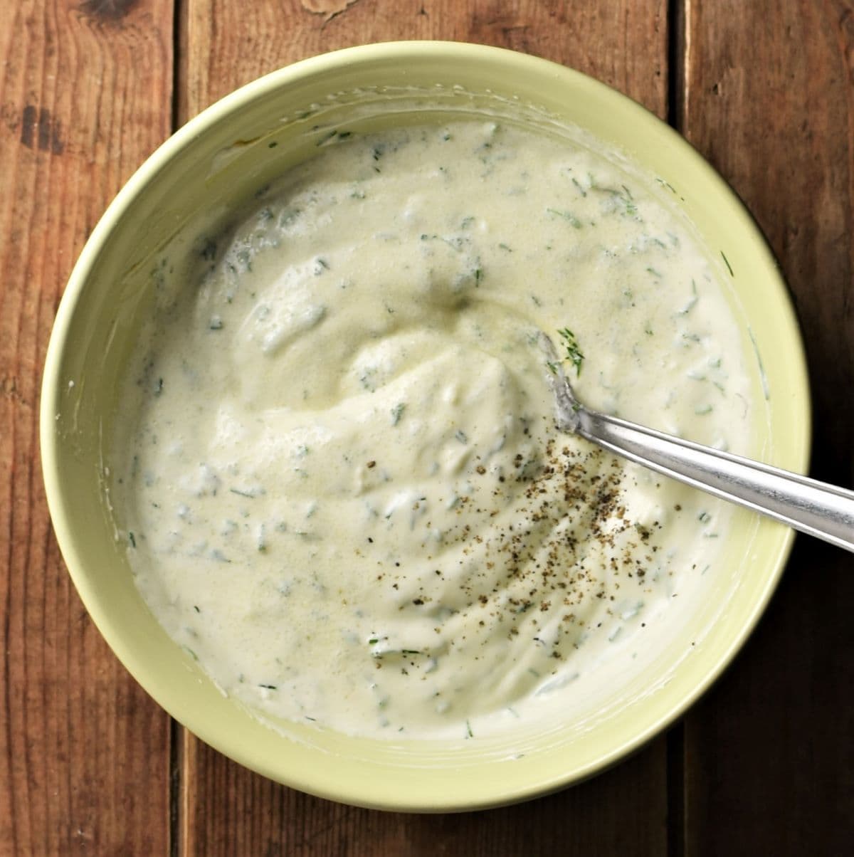 Making ranch dressing in yellow bowl with spoon.
