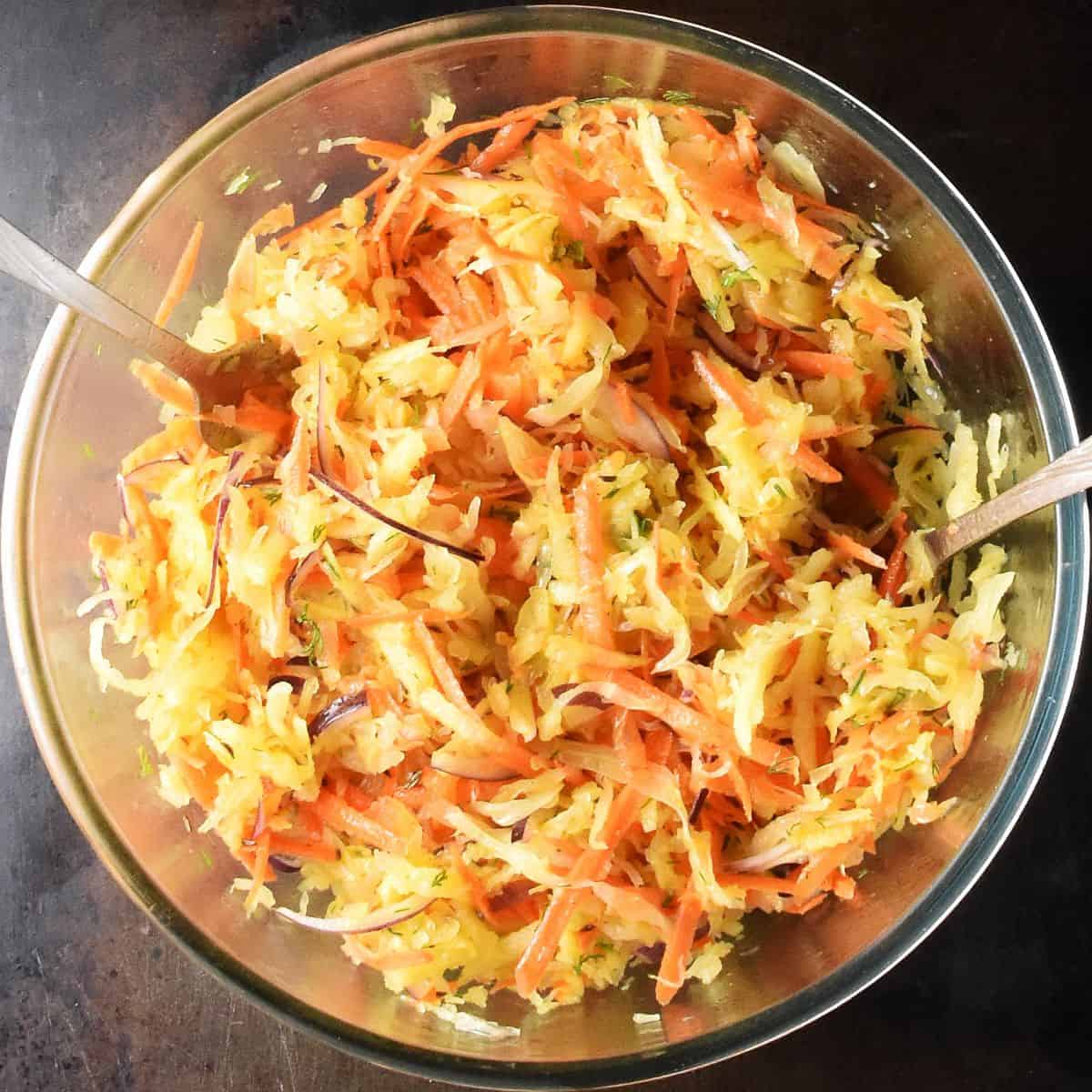Top down view of shredded sauerkraut salad in glass bowl with 2 forks.