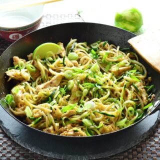 Chicken stir fry in wok with lime in background.