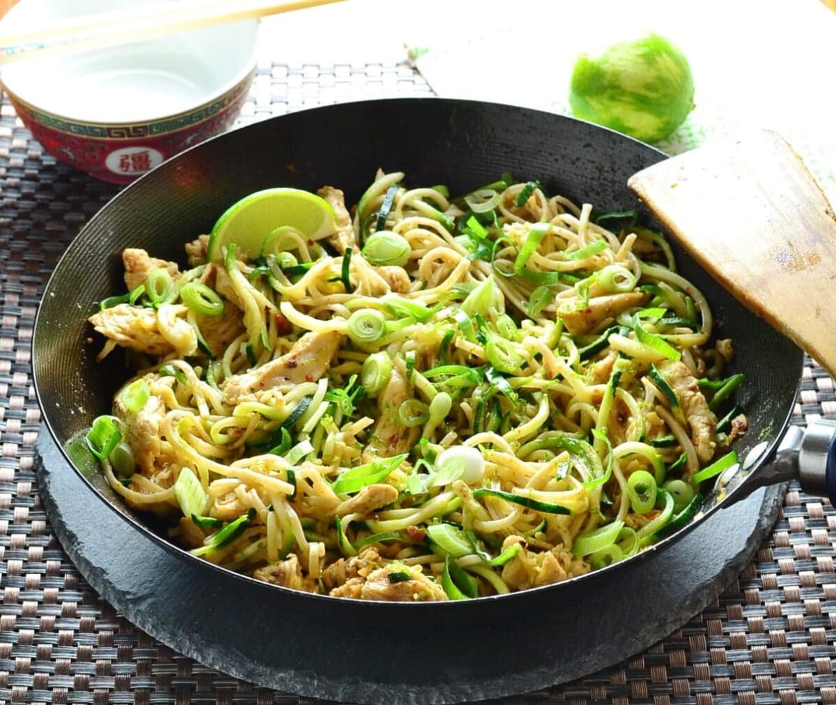 Chicken stir fry in wok with lime in background.