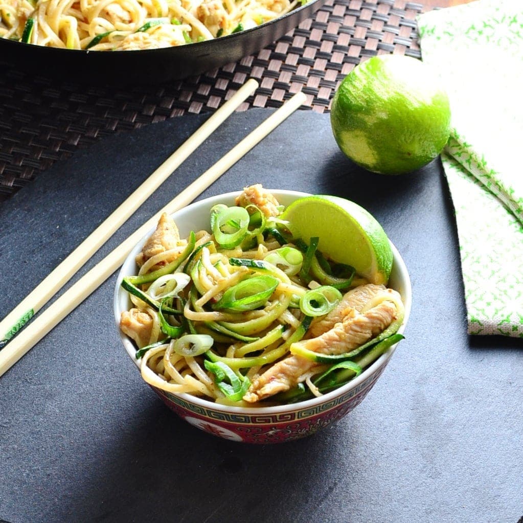 Hoisin chicken stir fry with lime, chopsticks and green cloth on black surface.
