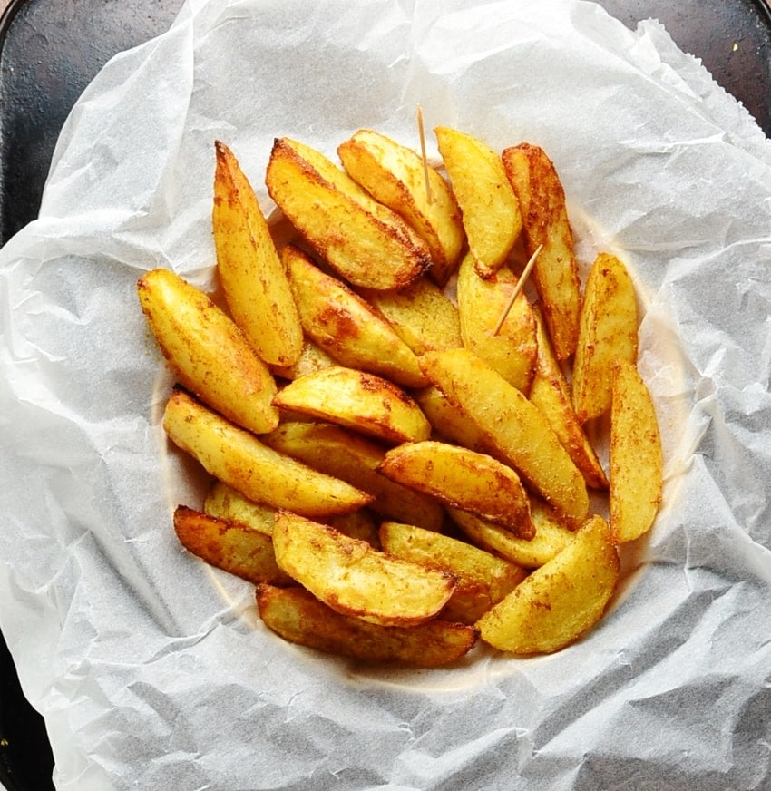 Spiced potato wedges on top of parchment paper.