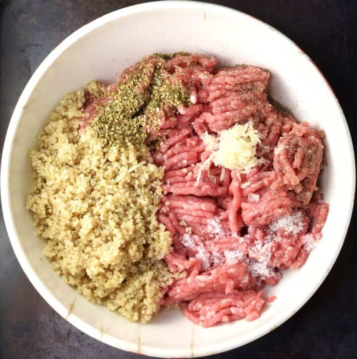 Ingredients for making quinoa turkey meatballs assembled in white mixing bowl.