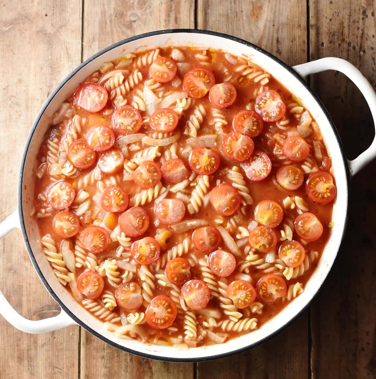 Fussili pasta with tomatoes in large white shallow casserole dish.