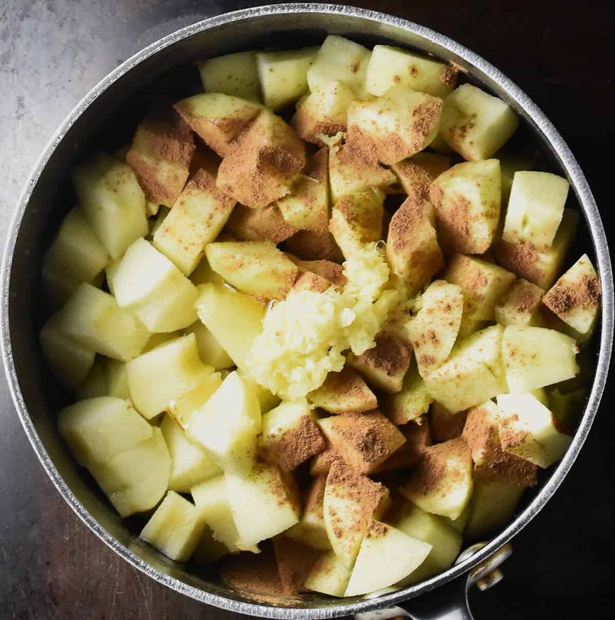 Top down view of cubed peeled apples with cinnamon in pot.