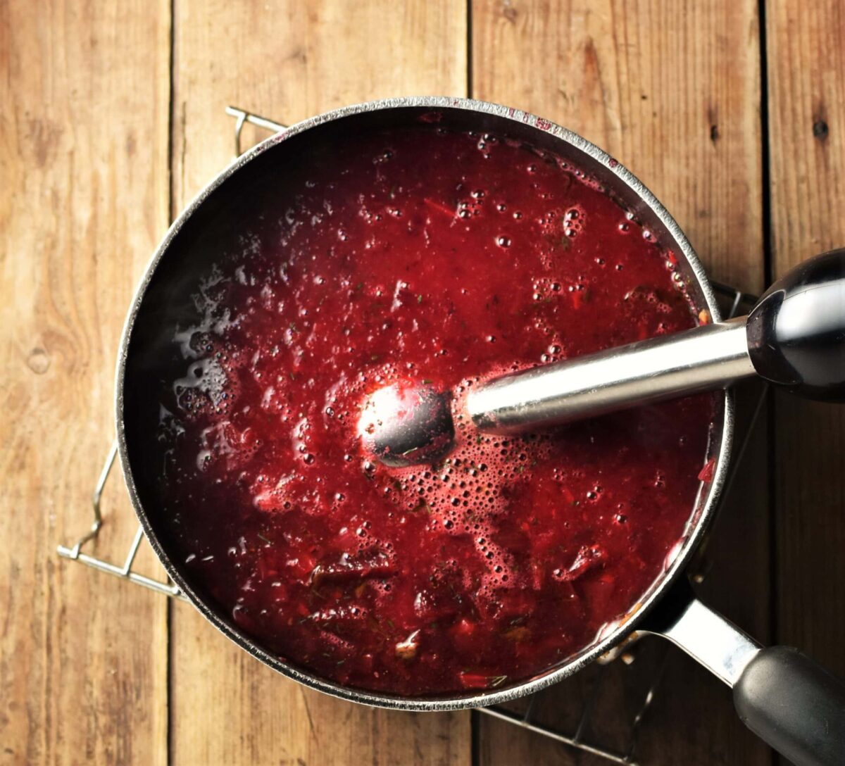Pureed beet soup in pot with hand blender end piece.