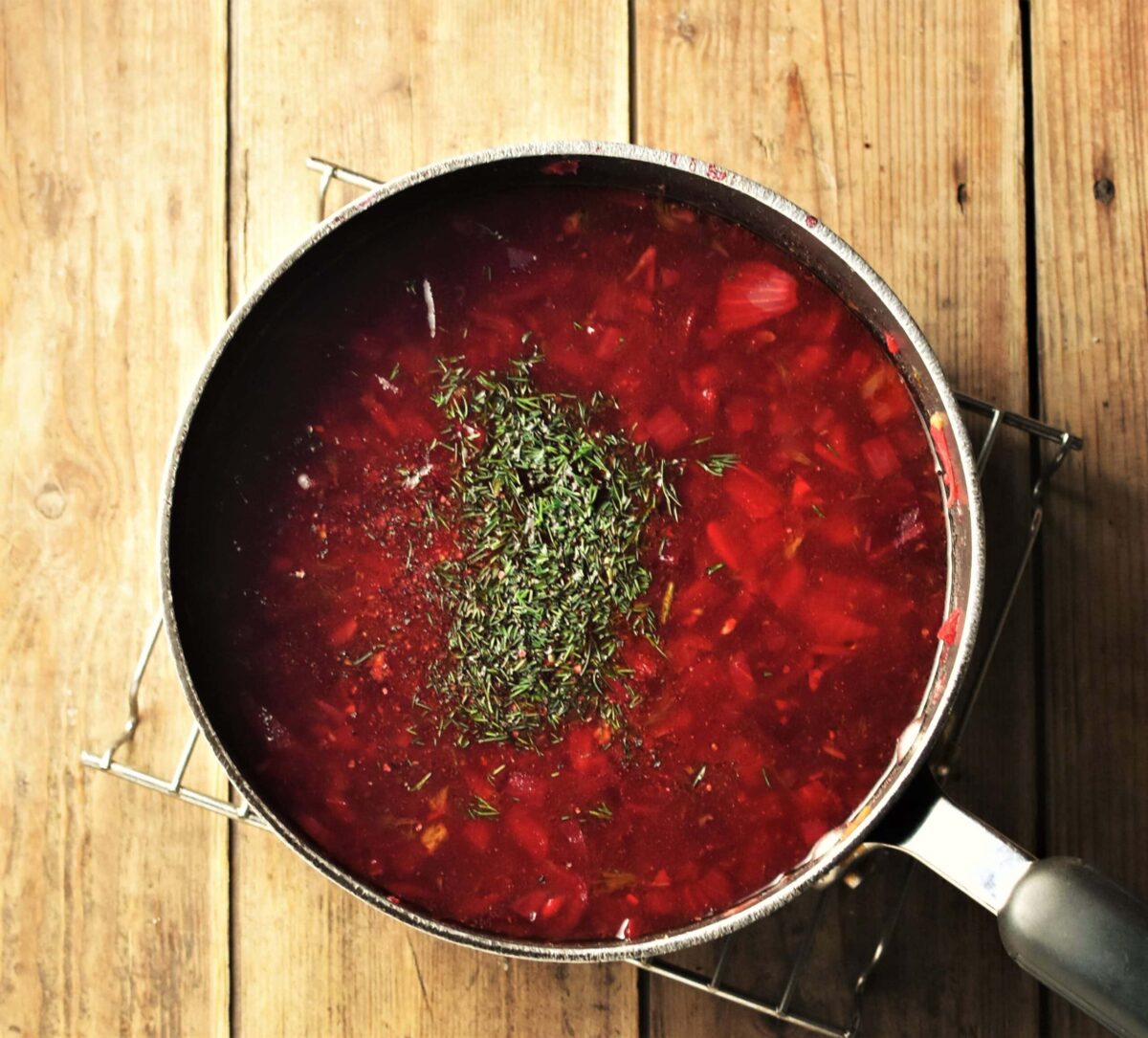 Beet soup with chopped dill in large pot.