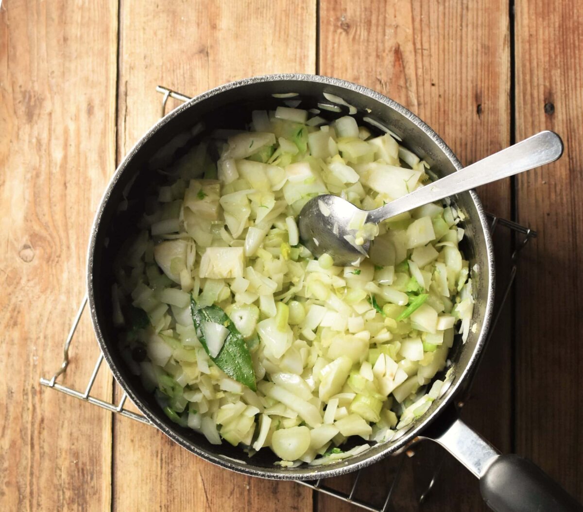 Chopped onion, celery and fennel in large pot with spoon.