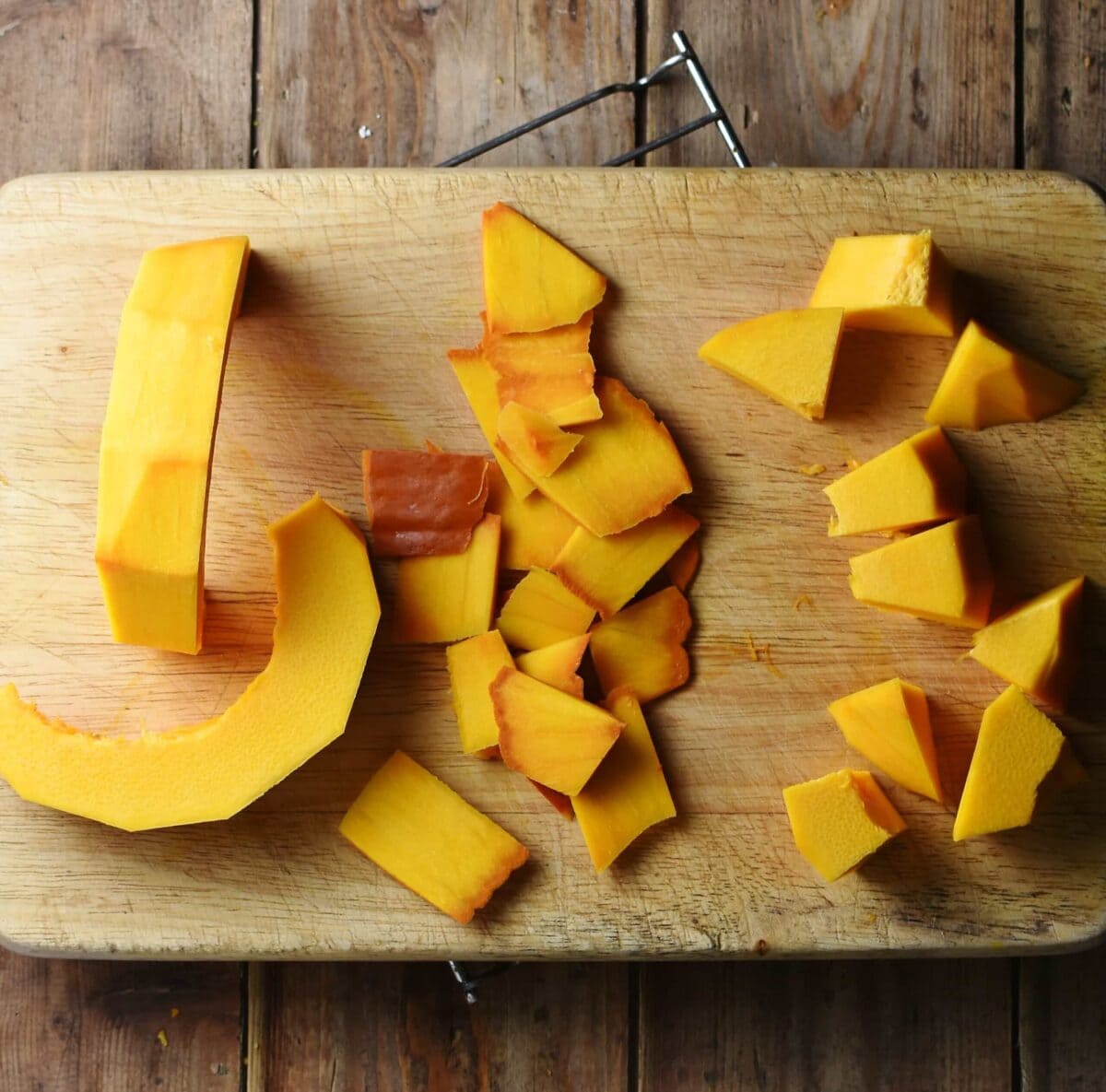 Peeled and chopped pumpkin on wooden board.