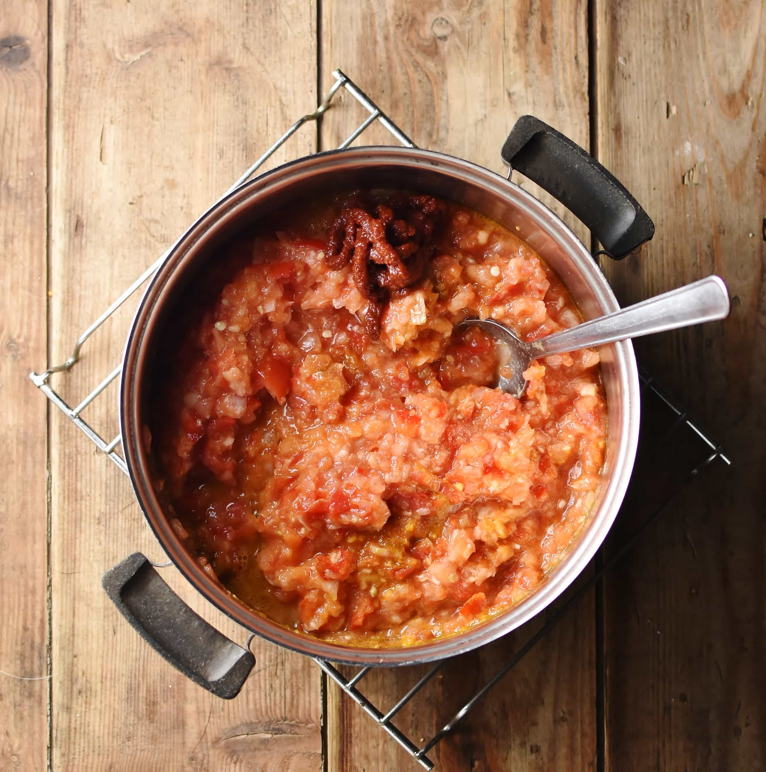 Puree tomato mixture in pot with spoon.