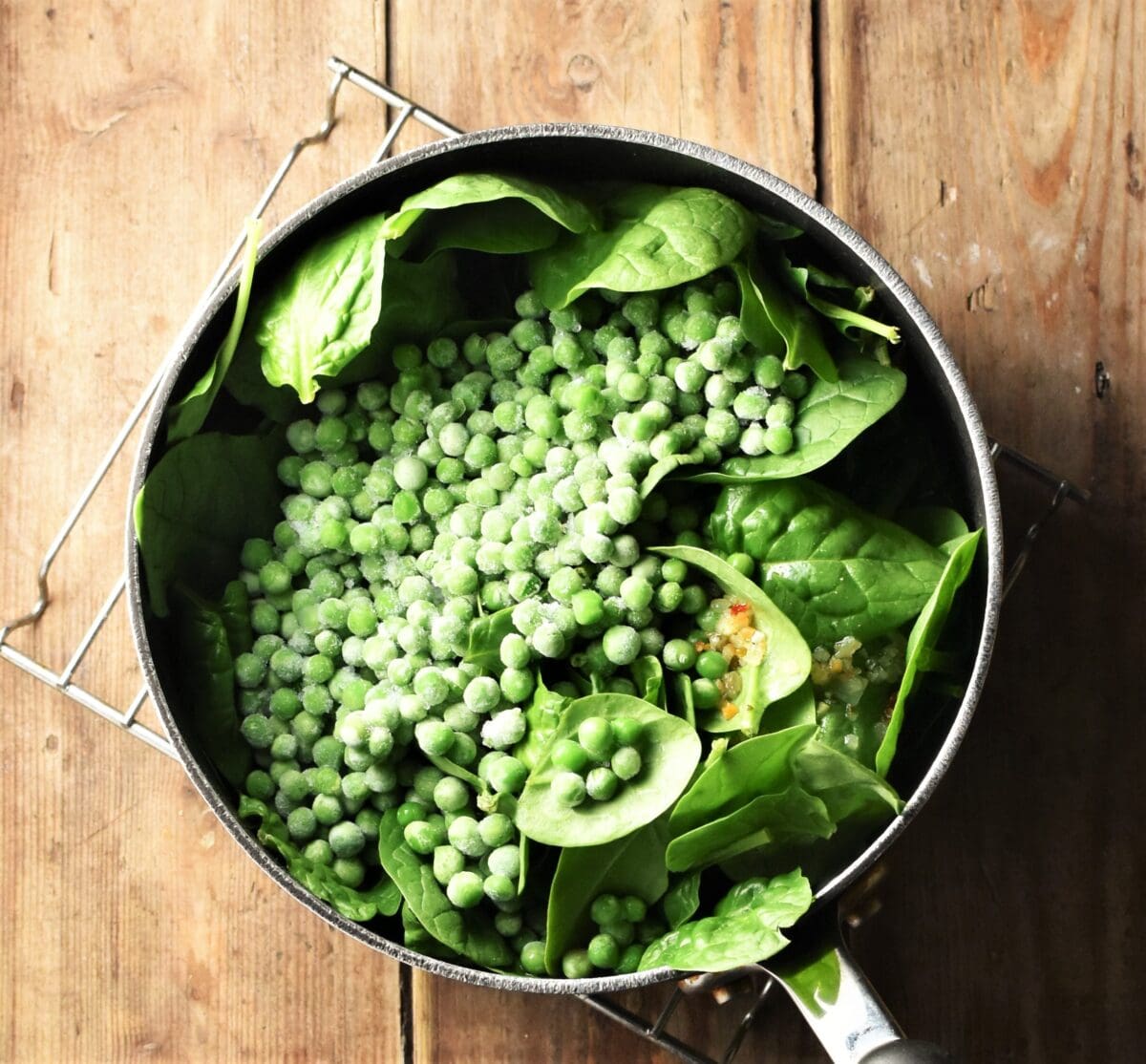 Fresh spinach and frozen peas in large pot.