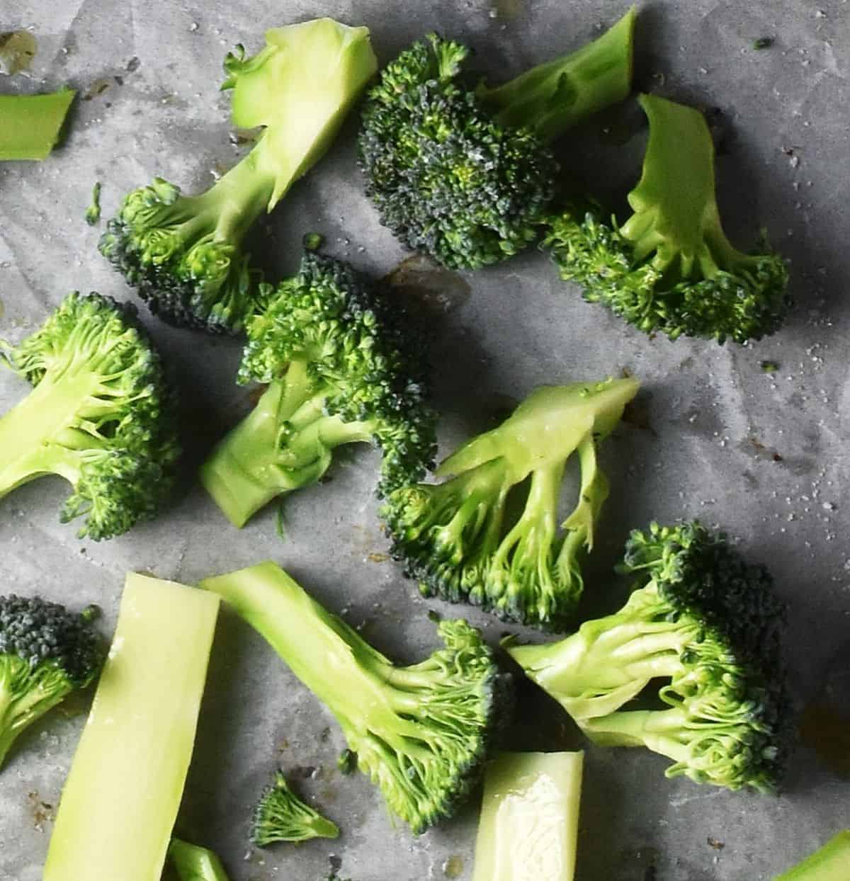 Top down view of raw broccoli pieces on parchment.