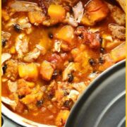 Chicken butternut squash casserole with black beans in white pot with grey lid and green cloth.