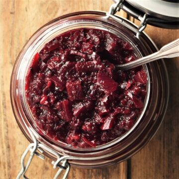 Top down view of beet chutney in open jar with spoon.