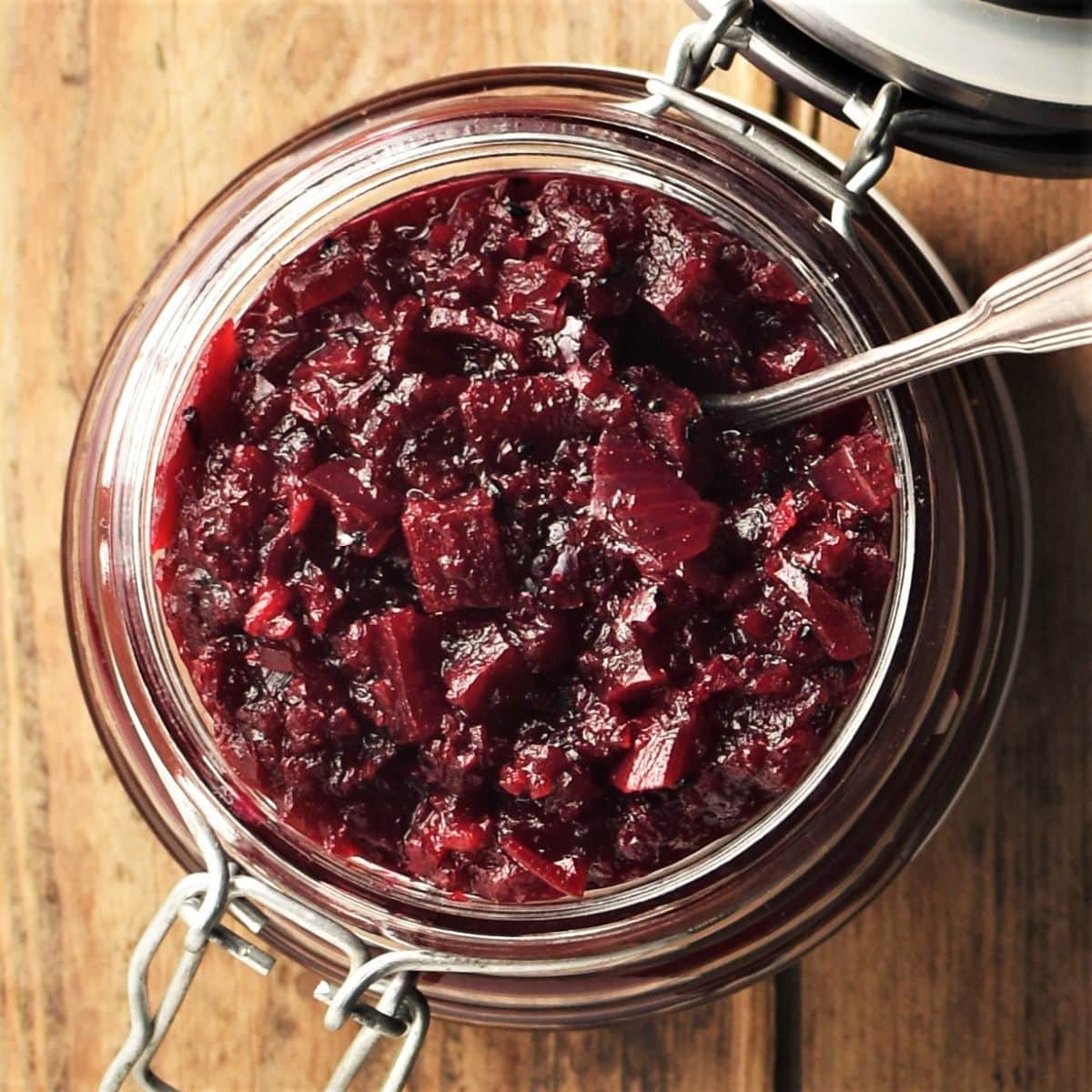 Top down view of beetroot chutney in open jar with spoon.