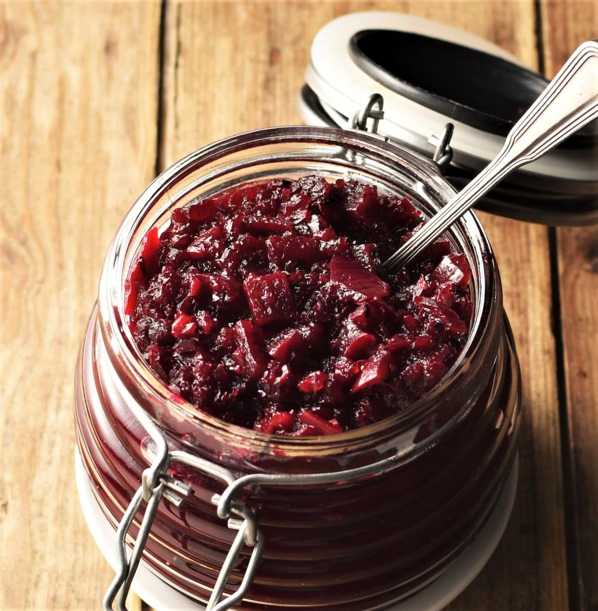 Side view of beetroot chutney in open jar with spoon.