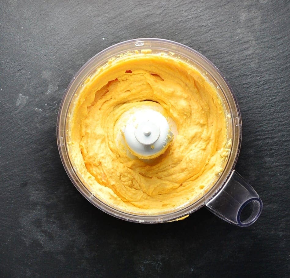 Deviled eggs mixture in blender bowl in grey surface.