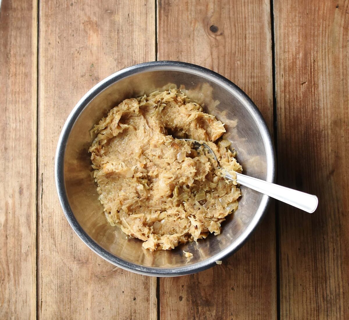 Sauerkraut mixture in metal bowl with spoon.