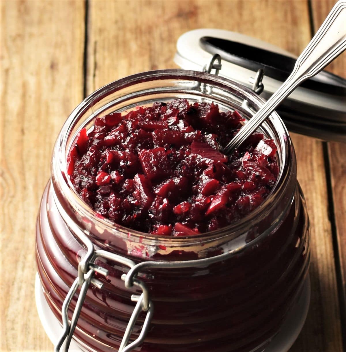 Close-up view of beetroot chutney in open jar with spoon.
