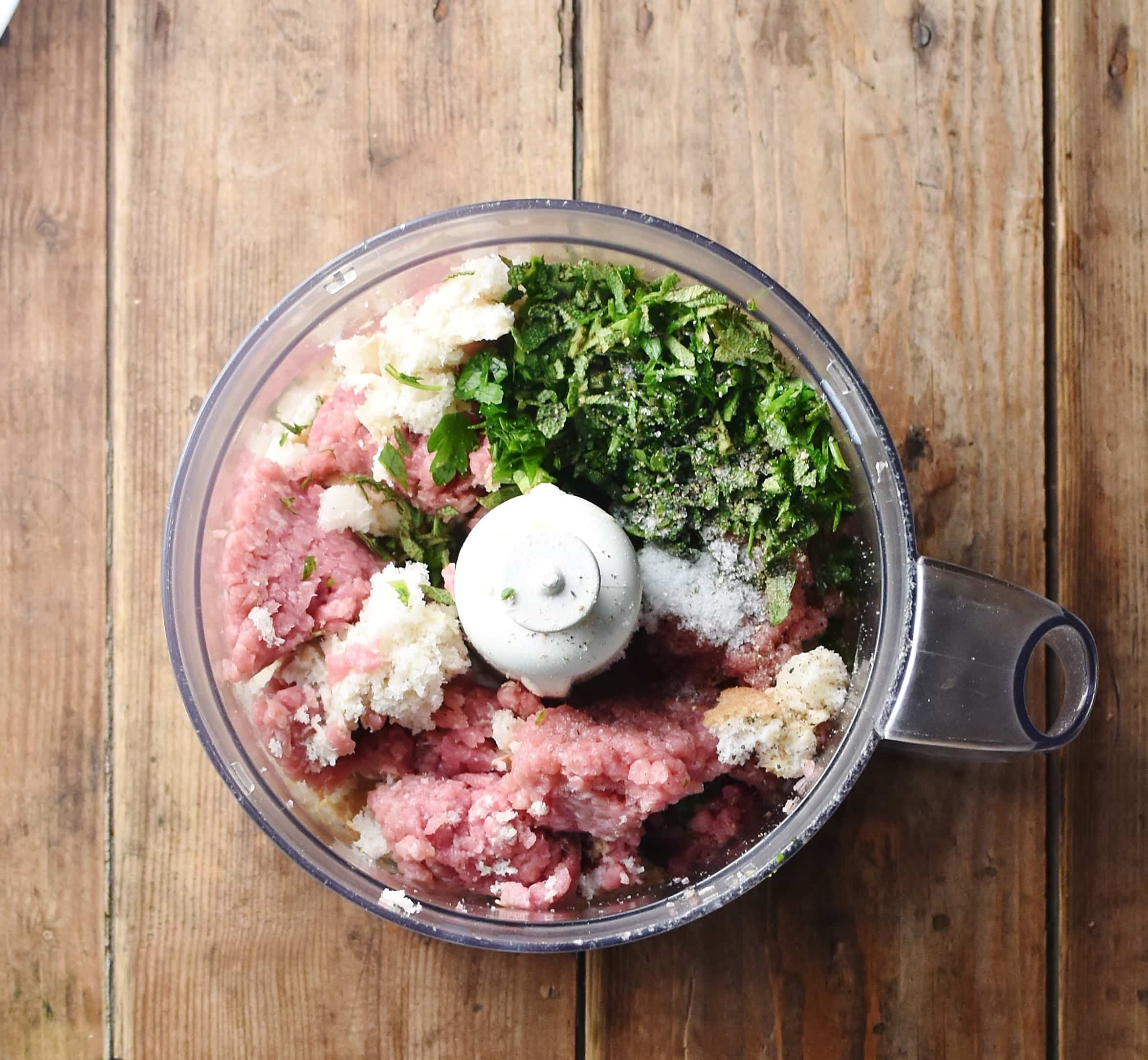 Ground turkey, chopped herbs and pieces of bread inside blender.