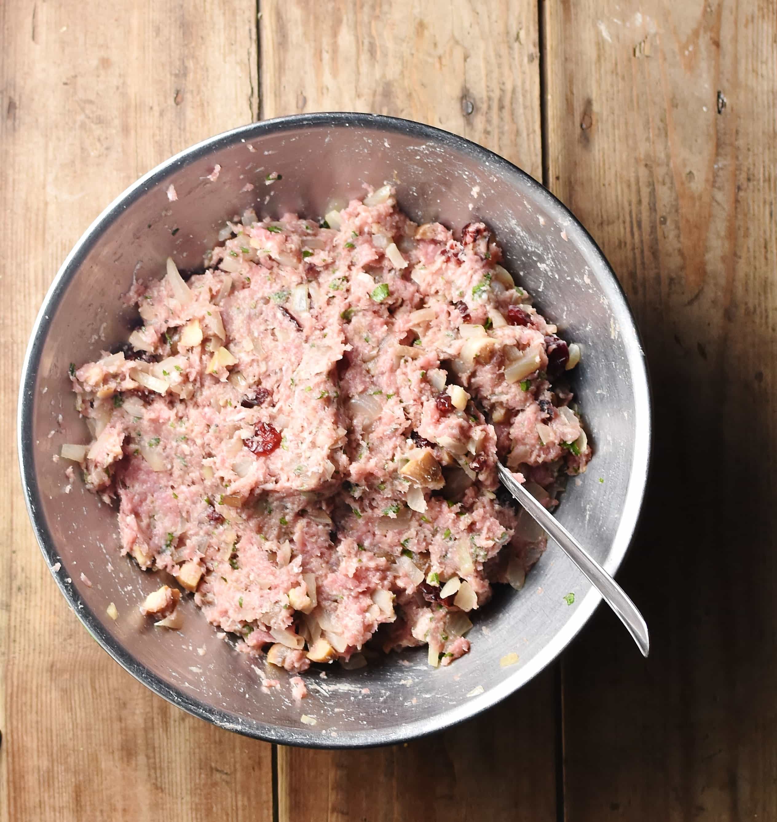 Stuffing mixture in large metal bowl with spoon.