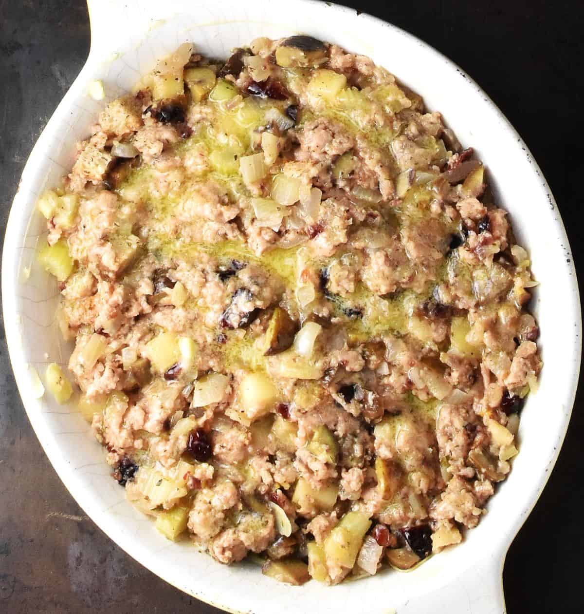 Top down view of vegan sausage stuffing in white oval dish.