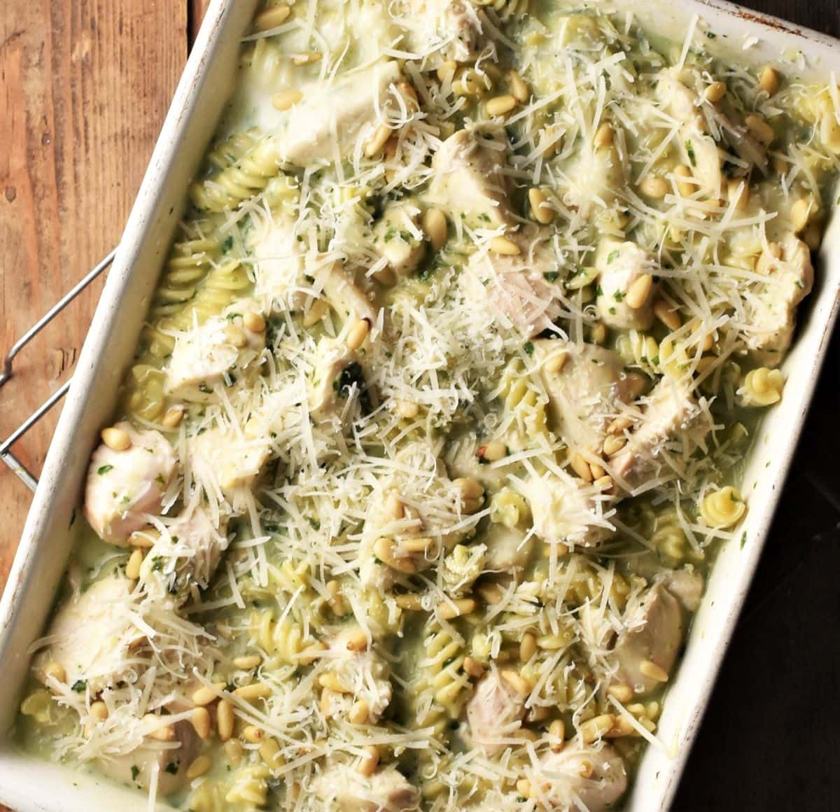 Creamy chicken pasta with pesto and parmesan in casserole dish.