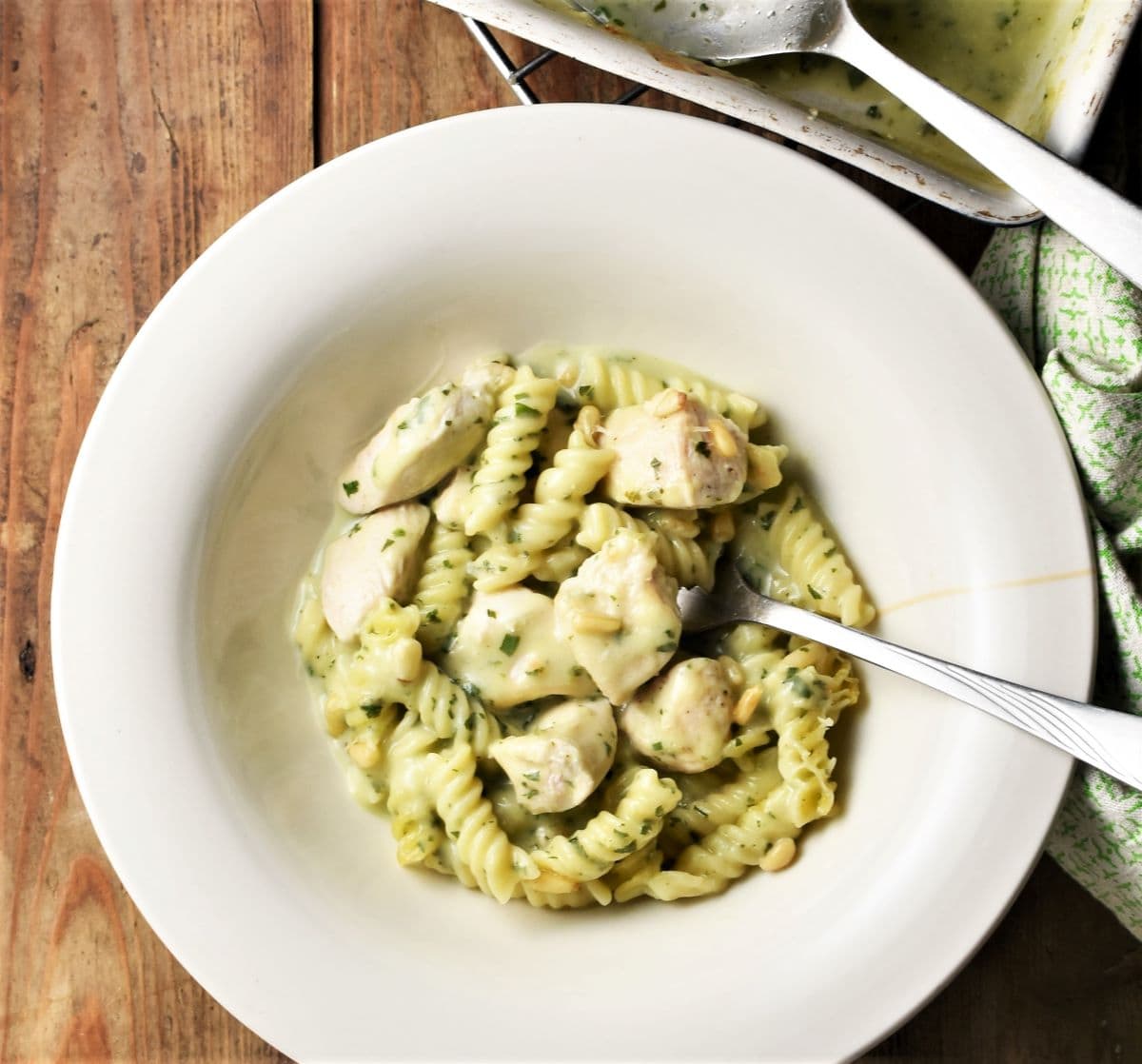 Creamy chicken pesto pasta in large bowl with fork.