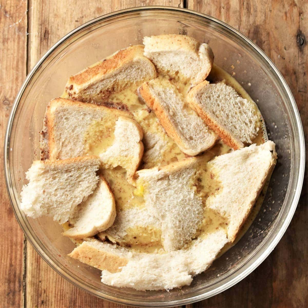 Bread pieces in mixing bowl with egg mixture.