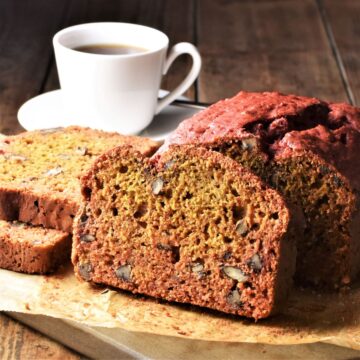 Side view of beetroot bread on top of parchment and cup of coffee in background.