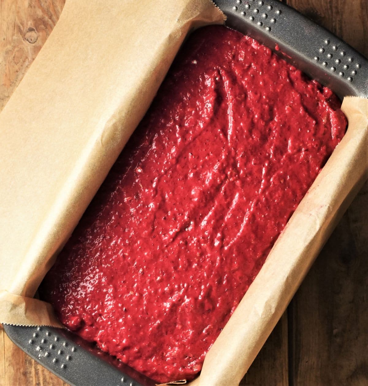 Beetroot batter in loaf pan lined with parchment paper.