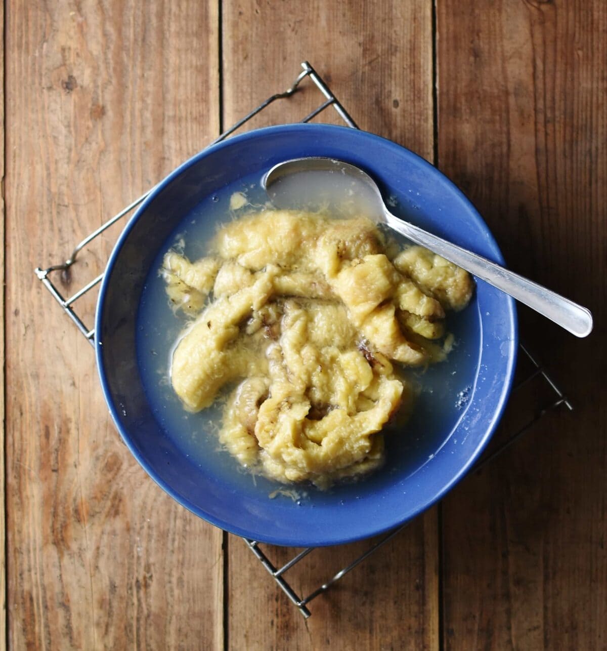 Cooked banana pulp with spoon in blue bowl.
