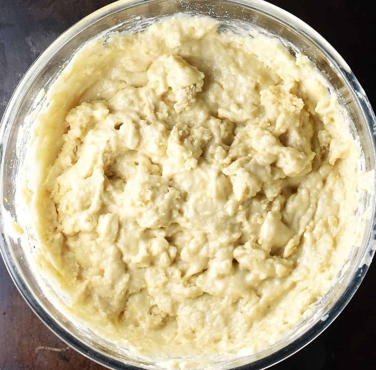 Thick batter for marzipan lemon muffins in glass bowl.