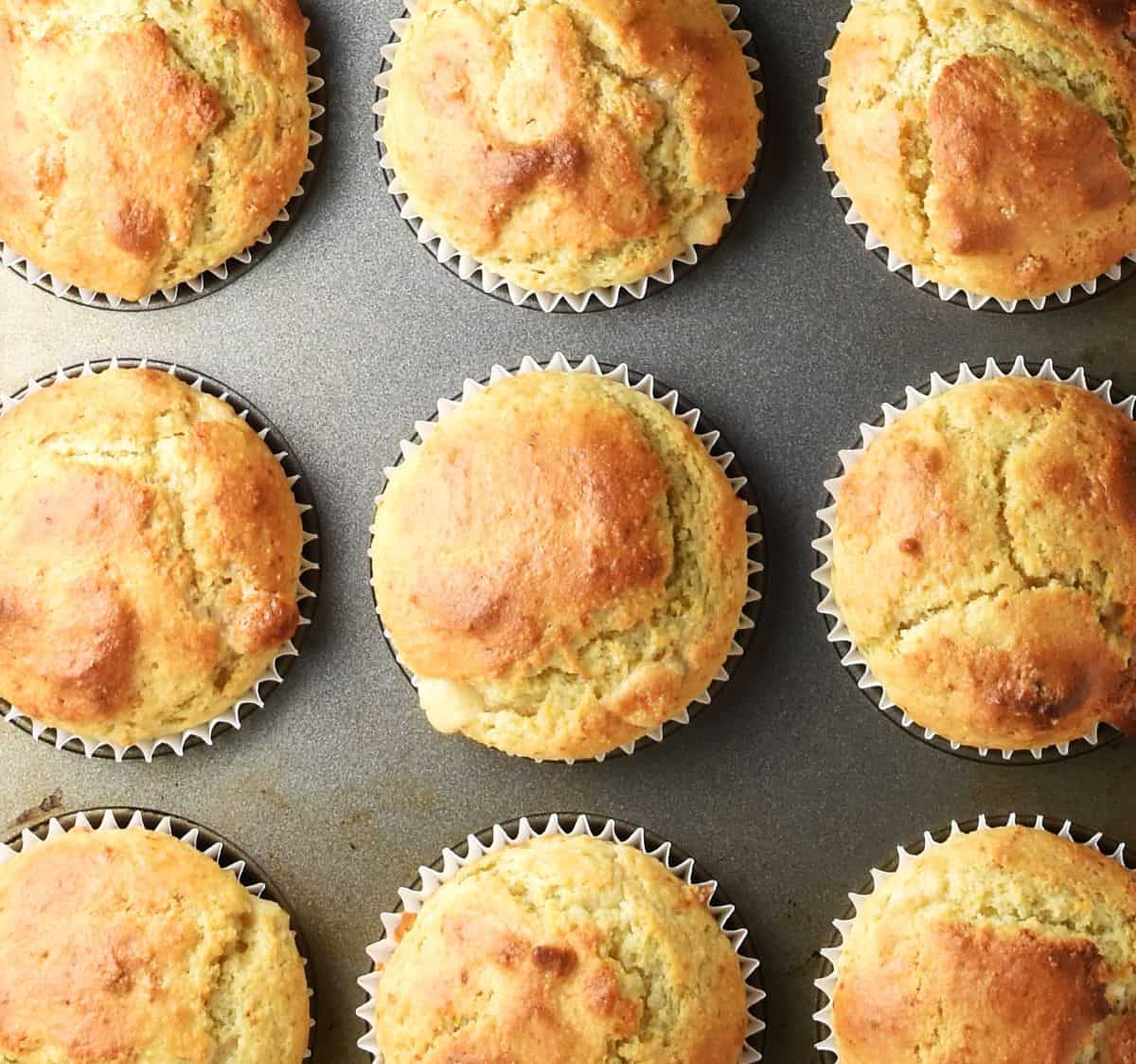 Top down view of baked muffins with marzipan in muffin pan.