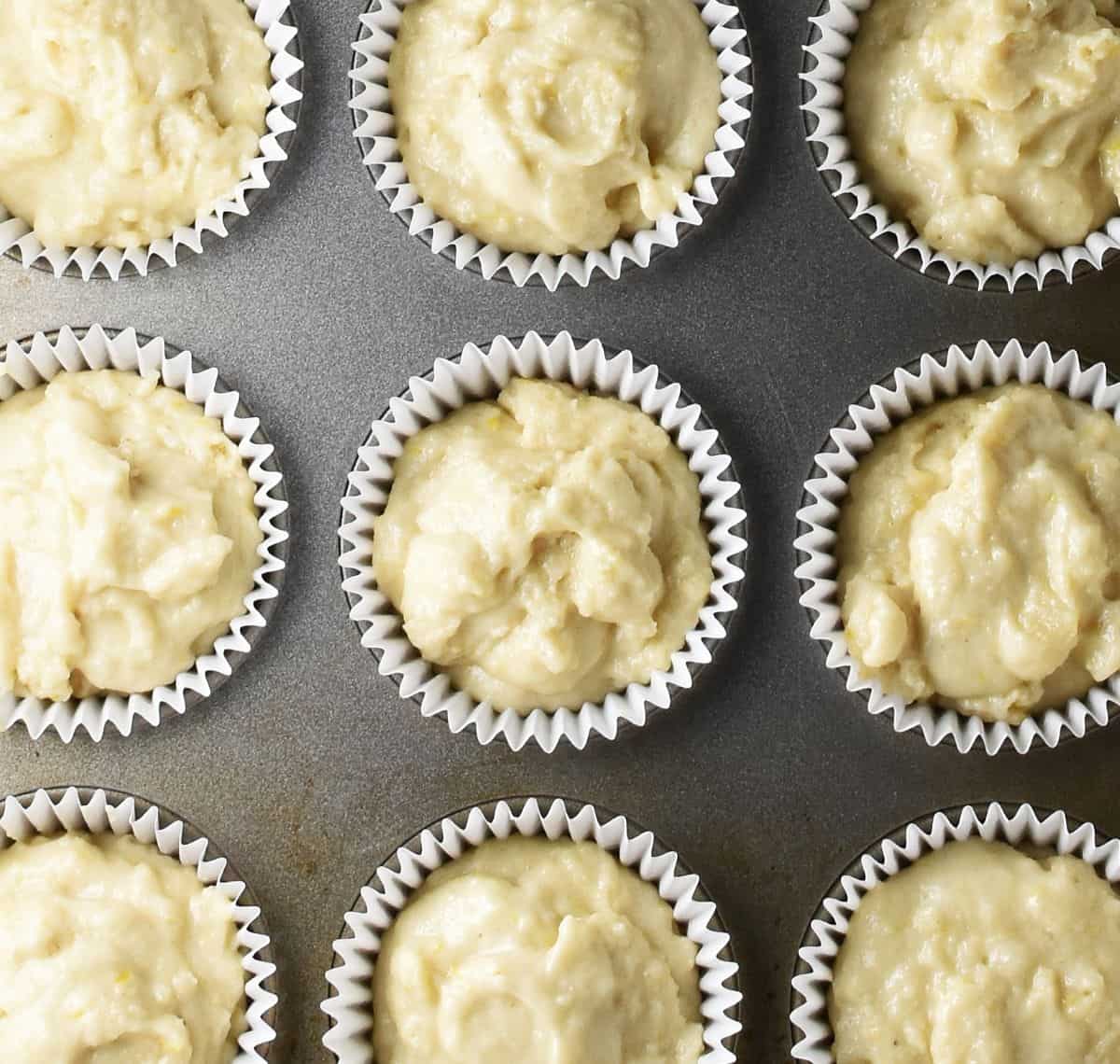 Raw marzipan muffin batter in paper cases in muffin pan.