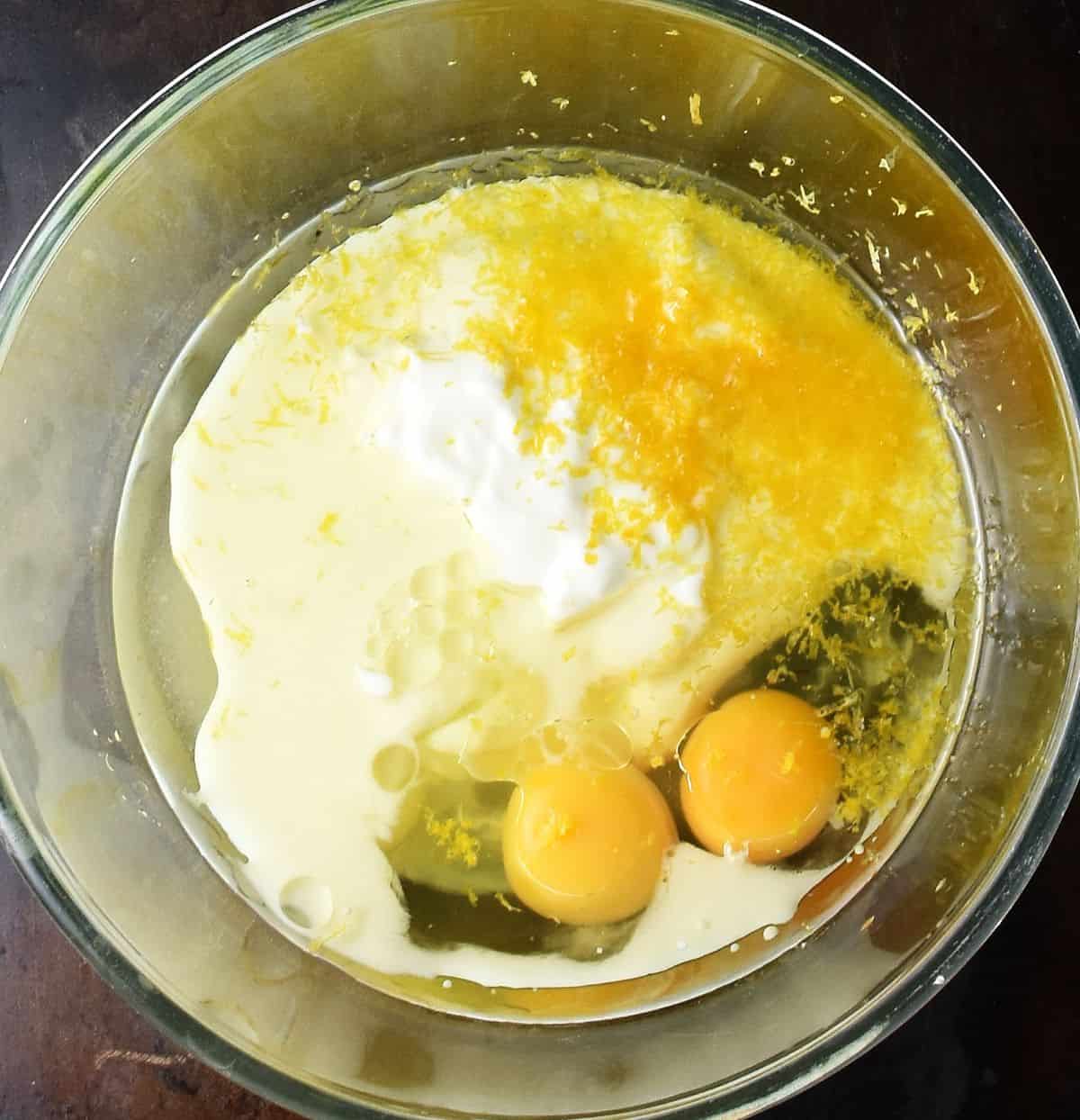 2 raw eggs, milk and lemon zest in large glass bowl.