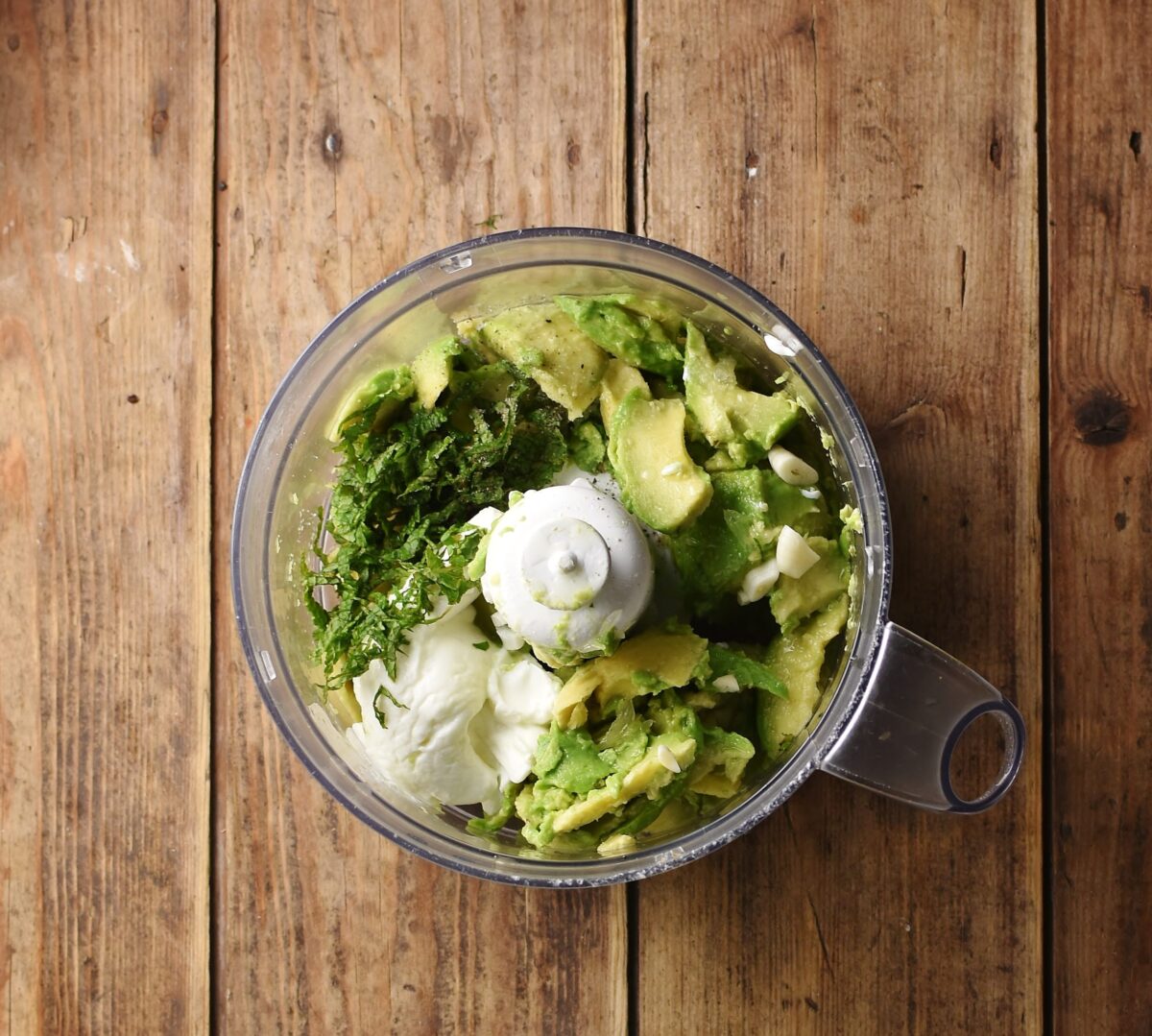 Chopped avocado, yogurt and herbs in blender.